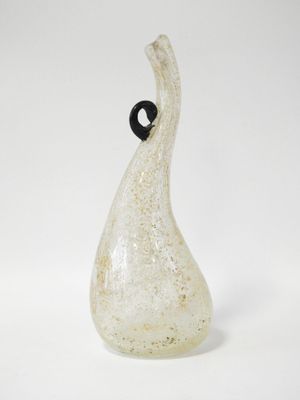 un vase en verre muni d'une anse noire, posé sur une surface blanche
