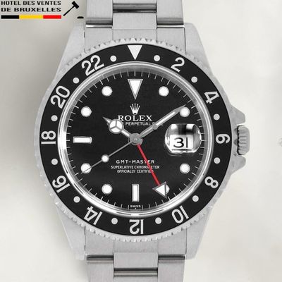 une montre Rolex avec un cadran noir et des aiguilles rouges