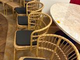 plusieurs chaises en osier et une table dans une pièce ornée d'un rideau rouge