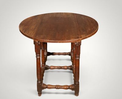 une vieille table en bois avec un plateau rond et des pieds tournés