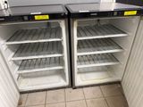 two open refrigerators in a kitchen with a lot of shelves