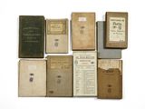 several old books sitting on top of each other on a white surface