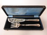 two silverware items in a black case on a white surface