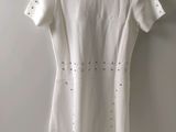 a white dress hanging on a hanger against a wall
