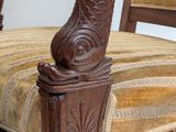 a wooden chair with a striped seat and arm rest