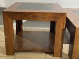 two wooden tables with glass tops on a tiled floor