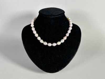 a close up of a necklace with pearls on a mannequin