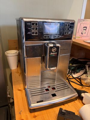 a coffee machine sitting on a wooden table next to a refrigerator