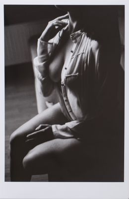 black and white photograph of a woman sitting on a chair smoking a cigarette
