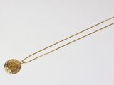 a gold necklace with a coin on it