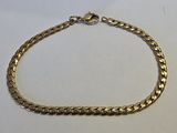 gros plan d'un bracelet en chaîne en or sur une surface blanche