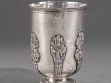 une coupe en argent ancienne posée sur une table, devant un fond gris