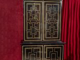 a black and gold cabinet in front of a red curtain