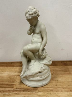 a statue of a boy sitting on top of a rock