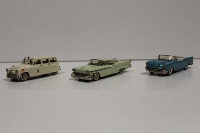 trois petites voitures posées sur une surface blanche