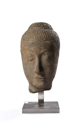 statue représentant une tête de Bouddha posée sur un socle, sur fond blanc