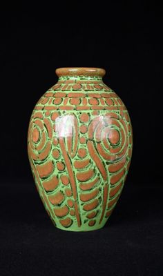 un vase vert et orange posé sur une surface noire