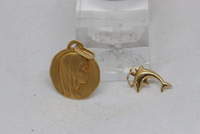 une breloque en forme de dauphin plaquée or et une pièce d'or posées sur un socle en acrylique transparent