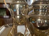 a silver plate with a silver tea pot and two silver cups