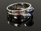 a close up of a ring with a sapphire and diamonds