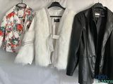trois vestes suspendues à un porte-vêtements sur fond blanc