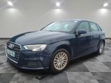 Une Audi bleue est garée sur un sol à damier dans un garage.