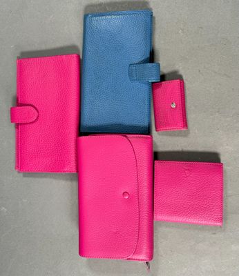 three pink and blue wallets sitting next to each other on a table
