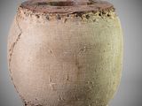 a brown and green vase sitting on a gray surface