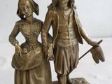 statue en bronze d'un garçon et d'une fille avec un chapeau et une canne