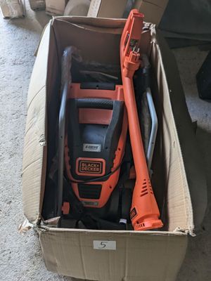 un souffleur à fil orange et noir posé dans une boîte en carton