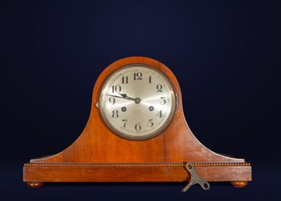 une petite horloge en bois surmontée d'une clé