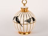 une cage à oiseaux contenant des oiseaux, posée sur une surface blanche