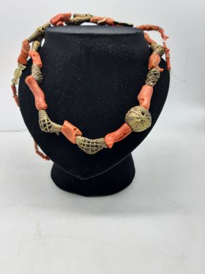 un collier orange et doré sur un mannequin noir