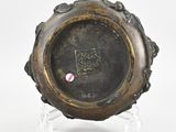 a bronze plate with a design on it on a clear stand