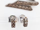 two pieces of silver and diamond jewelry on a white surface