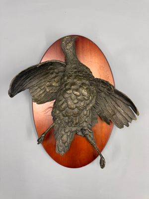 a bronze bird mounted on the wall of a room