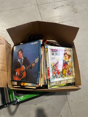 a cardboard box full of books and cds on the floor