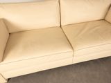 cream colored leather couch sitting in a corner of a living room