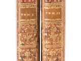 two old books sitting on top of each other on a white surface