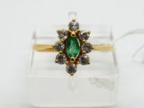 a close up of a ring with a green stone surrounded by white diamonds