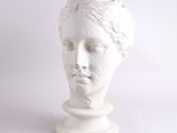 une sculpture blanche représentant la tête d'une femme, posée sur un socle