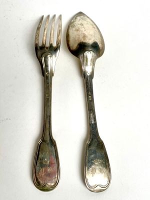 two spoons and a fork on a white table