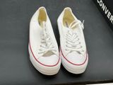 pair of white converses on a black surface with a box