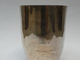 une tasse en argent posée sur une surface blanche