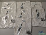 Quatre t-shirts blancs ornés de logos noirs et blancs sont posés sur une table