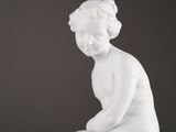 white marble statue of a boy sitting on a rock