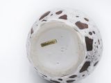 a white vase with brown spots on it on a white surface