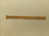 une image d'un bracelet en or sur une surface blanche