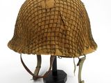 un vieux casque posé sur un socle noir, sur fond blanc