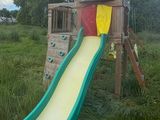 a wooden play structure with a slide in the middle of it